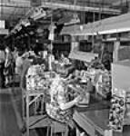 Male and female workers assembling and testing transmitters and receiving sets on the wireless assembly line in the RCA Victor plant July 1944