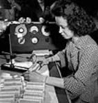 Female operator Muriel Bis of Montreal measuring coils of stirling wire used in radio transmitters assembled at the RCA Victor plant July 1944