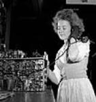 Female worker Eileen Eve of Montreal testing a transmitter-receiver radio set at the RCA Victor plant before the set is shipped July 1944