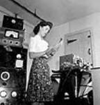 Female worker takes notes during a vibration test of a radio transmitter receiver set at the RCA Victor plant July 1944