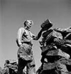 Workman Gus Erickson stacking up a pyramid of peat moss bales juil. 1944