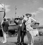 The Honourable C.D. Howe speaking with unidentified male official on the dock during the launching of a tug from the Central Bridge Company Aug. 1944