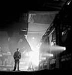 Workman observes ladle pouring molten steel at the Stelco Steel Company of Canada's openhearth furnaces mars 1944