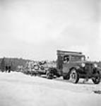 Truckhaul of truck hauling sleighs loaded with logs across a frozen Sloe Lake ca. 1943