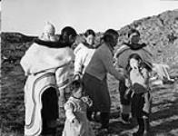 Inuit women [Includes Ekuma Parr, Qilimmiumi Samayualie, and possibly Saimaiyak Akesuk, Lizzie Tarriasuk and Oqsuralik Ottokie] and children in Cape Dorset, Northwest Territories [Cape Dorset (Kinngait), Nunavut] 1948.