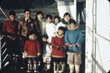 Inuits à bord du C.G.S. C.D. HOWE à Grise Fiord (Ausuittuq, Nunavut]. [Famille Kyak de Tununiq (Pond Inlet). Dernier rangée, de gauche à droite: Moses, Kyak, Mary, Letia avec Elizabeth sur son dos, et Leah. Premier rangée, de gauche à droite: David, Carmen, Timothy, et Lilly.] 1958.