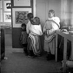 Une artiste inuite et mère examinant « Oies effrayées par un renard » de Kenojuak 1960