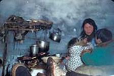Picture of interior of an Igloo with a woman [identified as Flossie Pappiklok] and children vers 1937