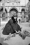 L'infirmière militaire Marie-Antoinette Sirois de l'Hôpital général canadien no 6 nourrissant les pigeons à la place Saint-Marc lors d'un congé à Venise, Italie March 24-26, 1919.