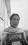 Woman [Tuurnagaaluk] holding a small chalk board with the number 6009 at Pond Inlet (Mittimatalik/Tununiq), Nunavut, August 1945 30-31 August 1945