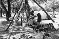 Nurse is checking a baby and mother outside of a tent on the Red Earth Reserve, Sask [ca. 1965]