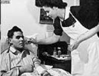 Member of Victorian Order of Nurses treating a patient in his home Jan. 1945