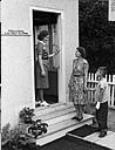 An Alberta Provincial District Nurse greets a youthful patient and his mother Sept. 1947