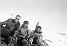 Gavin White sitting on the ground with two unidentified Inuit boys [graphic material] 1950