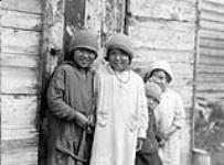 Four Inuit children, all in knit hats, leaning against a wall, Lyon Inlet, N.W.T., [Nunavut], 1933 1933.