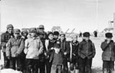 Externat fédéral Sir Joseph Bernier (Turquetil Hall), groupe de garçons debout sur le terrain de jeux de l'école, Chesterfield Inlet (Igluligaarjuk), Nunavut, 5 septembre 1958 [Les étudiants comprennent: Joe Ataguttaaluk, Raymond Kaslak, Nicholas Pauktuut Arnatsiaq, Paul Manotick, Piita Irniq, Francois Nanorak, Yvo Junuk, et Timothy Qirnnguk] 5 septembre 1958.