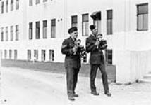 Les sergents Burt Johnson et Jack Dalgleish, tous deux membres de la Section de liaison avec la presse de l'Aviation royale, ont en main des appareils-photo Anniversary Speed Graphic October 27, 1940