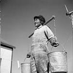 Anarouluk, an Inuit man employed by Hudson's Bay Company at Eskimo Point, N.W.T. carries pails of water with aid of a yoke [Anarauyak, the father of John Ahmak and Sam Anarauyak of Arviat] [graphic material] August 1, 1946