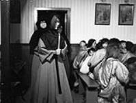 Twenty-year-old Sister Naya Pelagie becomes Canada's first Inuit nun [graphic material] : Sister Pelagie is shown as she enters the church at Chesterfield, N.W.T., to take the final vows on entering the order of the Grey Nuns March 1951