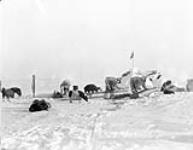 Inuit men icing qamutiik (sled) runners on at depot, Cape Dorset (Kinngait), Nunavut 1929