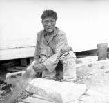 Inuk artist "Arnasungnark" Vital (Mukpa) cutting soapstone block for making an oil lamp Summer 1963