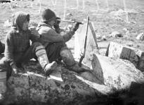 Two Inuit boys hunting. One is using a telescope 1944