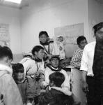 Inuit parents with their children seated on the floor in one of the school rooms at the Cape Dorset (Kinngait) Federal Hostel, where one of their dances was held, Nunavut, August 1961 août 1961.
