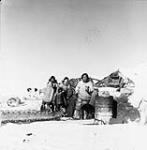 Inuit family outside home with a qamutiik (sled) 1949
