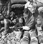 Inuk woman sitting with a group of children 1949