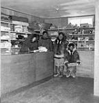 William Joss issuing Family Allowances in the new Hudson's Bay Company store at Read Island to two Inuit men and a child 1950