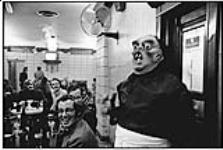 Waiter wearing a mask, Taverne de Paris, St. Denis St., Montreal April 19, 1973.