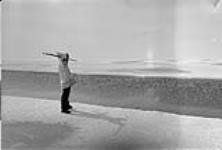 An Inuit man preparing to throw a harpoon at a sinking seal [Joseph Idlout, featured in the documentary "Land of the Long Day" by Doug Wilkinson] October, 1951.