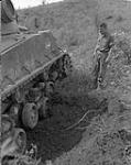 [Soldier examines mine crater and damaged running gear of an M4 Sherman tank] [1950-1953].
