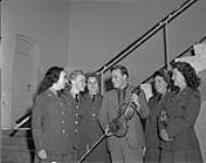 Club Ravenna, Utrecht - Special concert by Yehudi Menuhin for Canadian Troops - Famous violinist stops to talk to five CWAGs who attended his performance - Left to right - Pte. Dorien Myllard, St. Thomas, Ontario; Pte. Margaret Cross, Lethbridge, Alberta; Pte. Margaret Toth, Flin Flon, Manitoba; Yehudi Menuhin; Pte. Bernice O'Donnell of Toronto; Pte. Ruth Aird of Sudbury, Ontario - CWACs are the the No. 12 Detachment Canadian Army Shows called "Fun Fatigues" July 4, 1945.