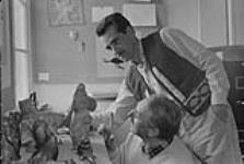 [Terry Ryan (above) and Mackenzie Porter (below) examining some carvings] [between August 24-October 3, 1960].