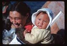 Woman carrying an infant in an "amauti" (woman's parka) [between June 17-October 31, 1960]