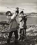 [Two boys playing with a bow and arrow, Kinngait, Nunavut] [between 1956-1960]
