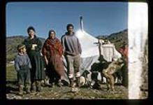 Men and women standing outside with huskies [between July 13-August 9, 1960]