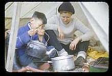 [Moshah Michael] showing Barbara Hinds how to make a polar bear stew, near Iqaluit, Nunavut [between August 18-19, 1960]