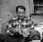 [Inuksiak carving a stone, Iqaluit, Nunavut] [between 1956-1960]