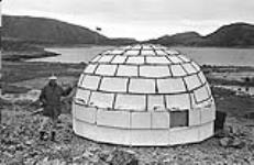 [Mackenzie Porter standing beside a Styrofoam igloo] [between 1956-1960]