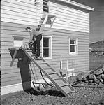 [Alma Houston climbing up a fire escape, Kinngait, Nunavut] [between 1956-1960]