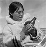 [Woman [Qaunaq Mikkigak] holding a bird sculpture, Kinngait, Nunavut] [between 1956-1960]