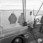 [Mackenzie Porter (left) and two men standing by a car on a boat, Iqaluit, Nunavut] [between 1956-1960]