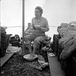[Barbara Hinds eating out of a bowl and soaking her feet inside a tent] [between 1956-1960]