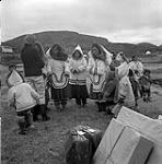 [Women and children standing outside] [Woman in dark jacket on left is Alma Houston. Wooman four over from Alma is Shooyoo Pootoogook] [between 1956-1960]