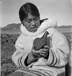 [Woman [Qaunaq Mikkigak] holding a small bird sculpture, Kinngait, Nunavut]3 [between 1956-1960]