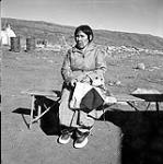 [Woman sitting on a bench sewing, Iqaluit, Nunavut] [between 1956-1960]