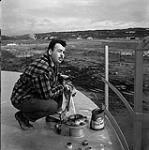 [Man measuring oil] [between 1956-1960]