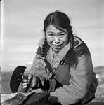[Taktu cleaning fat from seal skin with an ulu, Kinngait, Nunavut] [between 1956-1960]